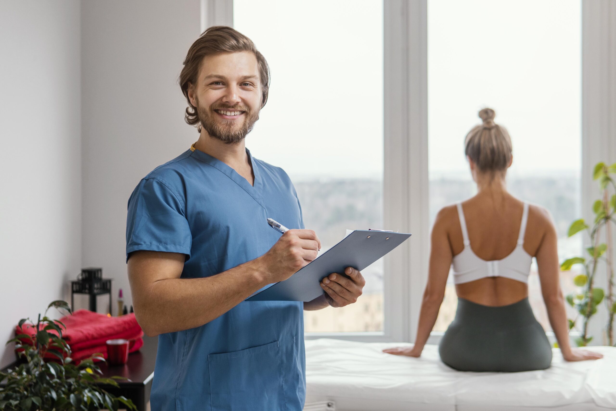 smiley-male-osteopathic-therapist-with-clipboard-female-patient-clinic